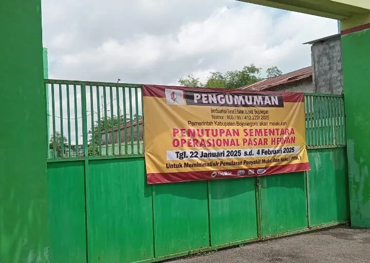 Banner di pagar sebuah pasar bertuliskan pemberitahuan penutupan pasar hewan tersebut akibat Penyakit Mulut dan Kuuku (PMK) pada ternak.
